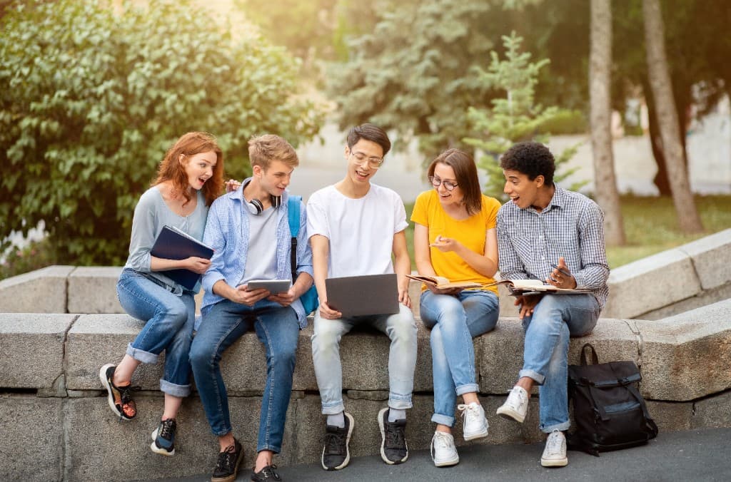 Students collaborating outdoors with a laptop